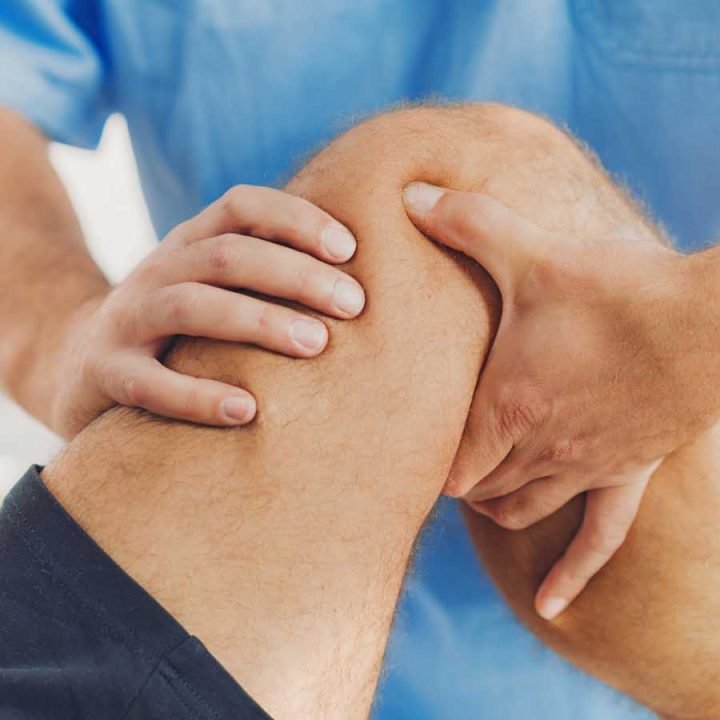 Physiotherapist doing healing treatment on patient leg. Therapist wearing blue uniform. Osteopathy, Chiropractic leg adjustment
